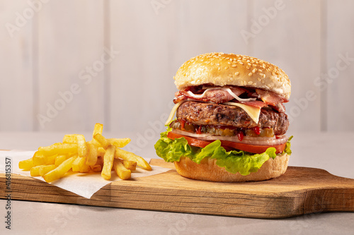 Close-up home made beef burger and fries on wooden board, clear light background