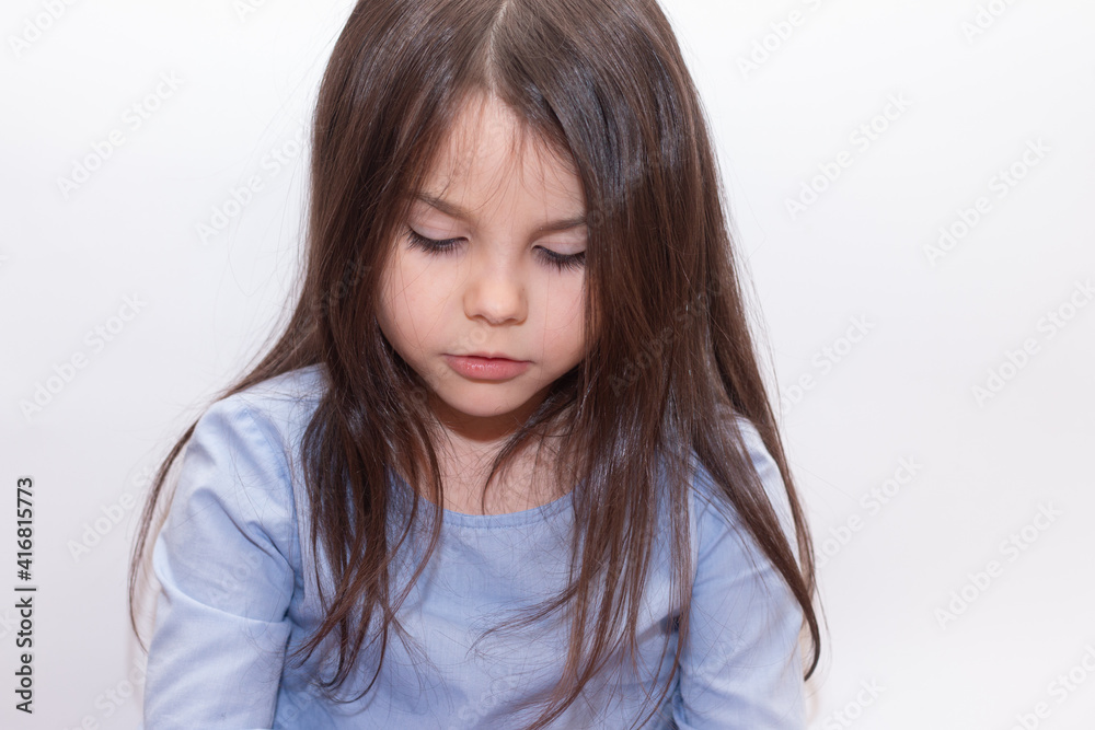 Beautiful little cute girl with long smooth hair looks down with interest Beautiful little cute girl with long smooth hair looks down with interest