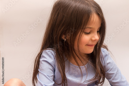 Little Hispanic girl on a white background in the studio, smiling, looks to the side