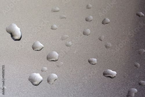 Drops in row on metal surface with shallow depth of field