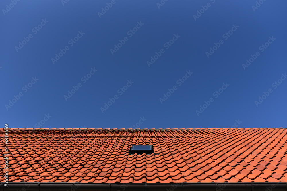 tile roof of house with window attic against the blue sky tile roof of house with window attic against the blue sky