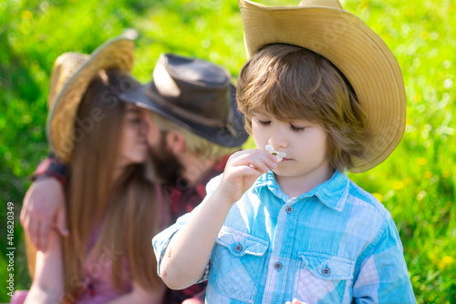 Gardener family on picnic outdoor. Summertime parent with kid in garden or park. Parenthood together leisure concept. Vife husband kiss. photo