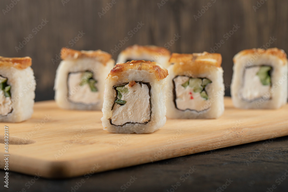 Delicious dragon sushi rolls with eel on wooden cutting board Delicious dragon sushi rolls with eel on wooden cutting board
