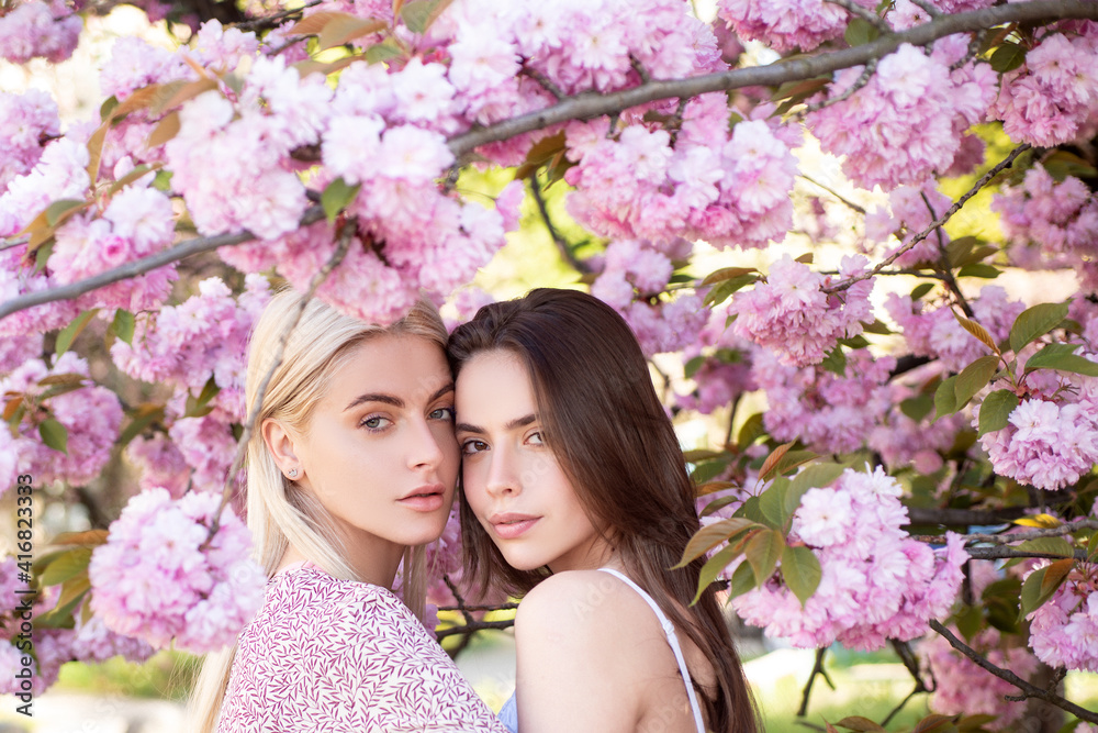 Obraz premium Young girls and spring flowers. Beautiful sensual sexy woman in pink flowers in summer blossom park.