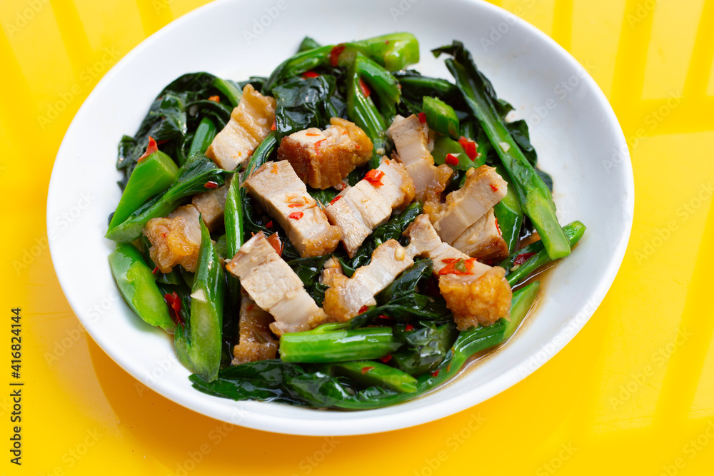 Dish of Stir fried chinese kale with crispy pork belly Dish of Stir fried chinese kale with crispy pork belly