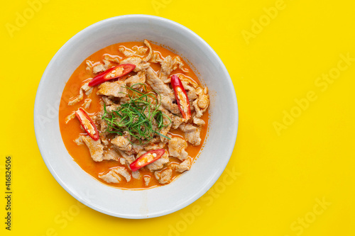 Panaeng Curry with pork in white bowl on yellow background.