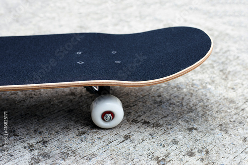 Black skateboard on cement ground.