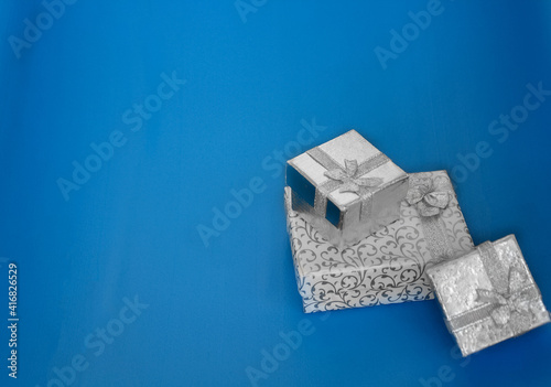 Fototapeta Naklejka Na Ścianę i Meble -  3 silver gift boxes on the blue background. silver jewelry boxes with copy space