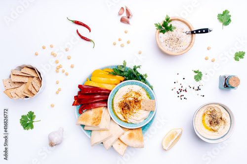 Various bowls of homemade hummus and Baba ghanoush. Traditional hummus with thyme, olive oil and paprika, vegetables, herbs, pita and crisp bread. Middle Eastern authentic Arabic cuisine.