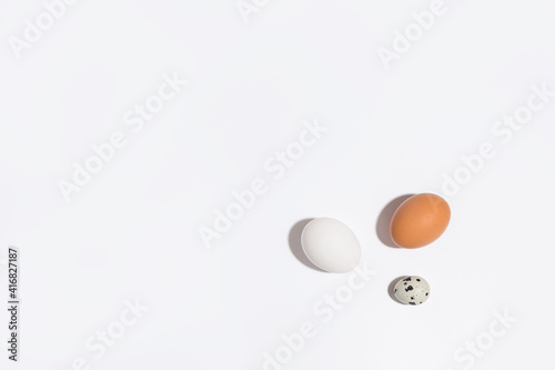 Three different eggs on a white background . Chicken and quail eggs on a light background with shadows. Lots of free space for text and copy space 