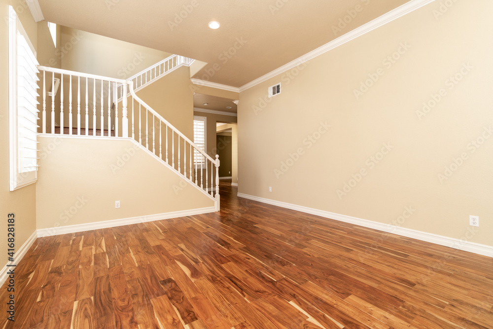 Large empty room with wood floor, molding and windows and stairs ...