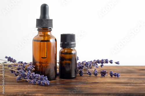 Essential oil with a dropper and lavender branches on a wooden table and white background with copy space. Brown glass cosmetic bottle, serum