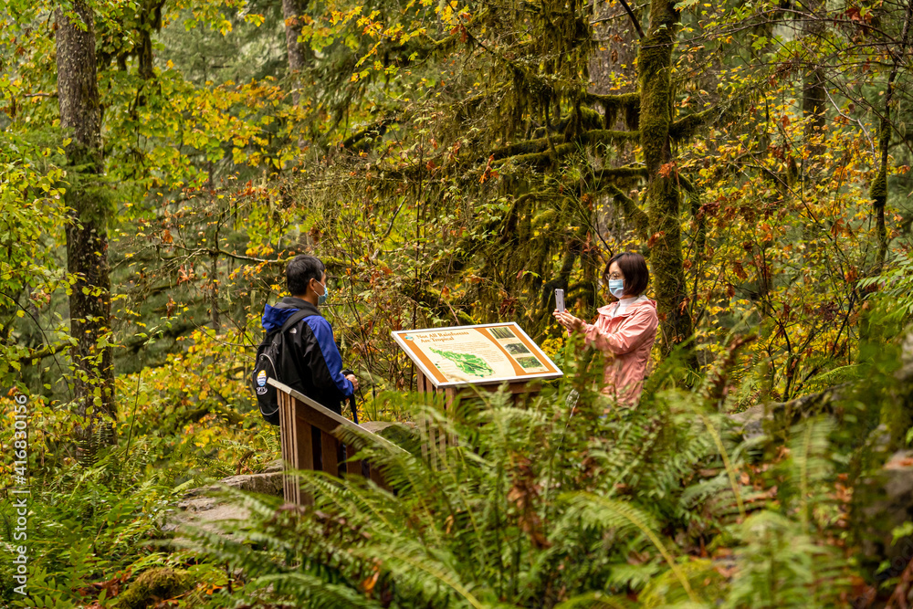 Silverton, Oregon - 10/18/2020:  A japanese man and woman at a rainforest sign in Silverfalls State Park near Silverson Oregon