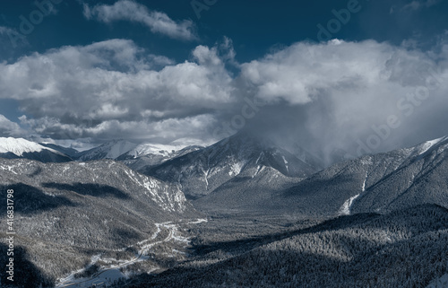 Caucasus Mountains. View from the Northern slope of the Arkhyz ski resort to the snowy mountain forests. Panoramic view of Arkhyz. Winter mountain landscape. A snow cloud over the mountain. © mazurevanasta