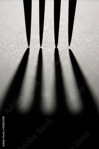 Foto Vertical conceptual monochrome close-up photo of a casting shadow tines of dinne