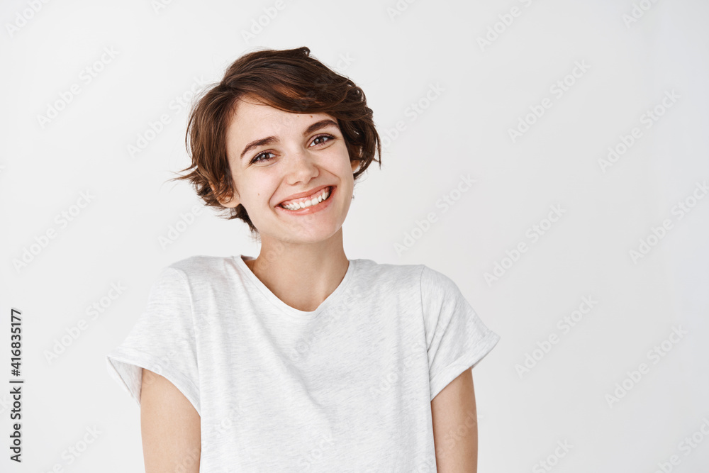 Portrait of authentic happy woman without makeup, smiling at camera, standing cute against white background Portrait of authentic happy woman without makeup, smiling at camera, standing cute against white background