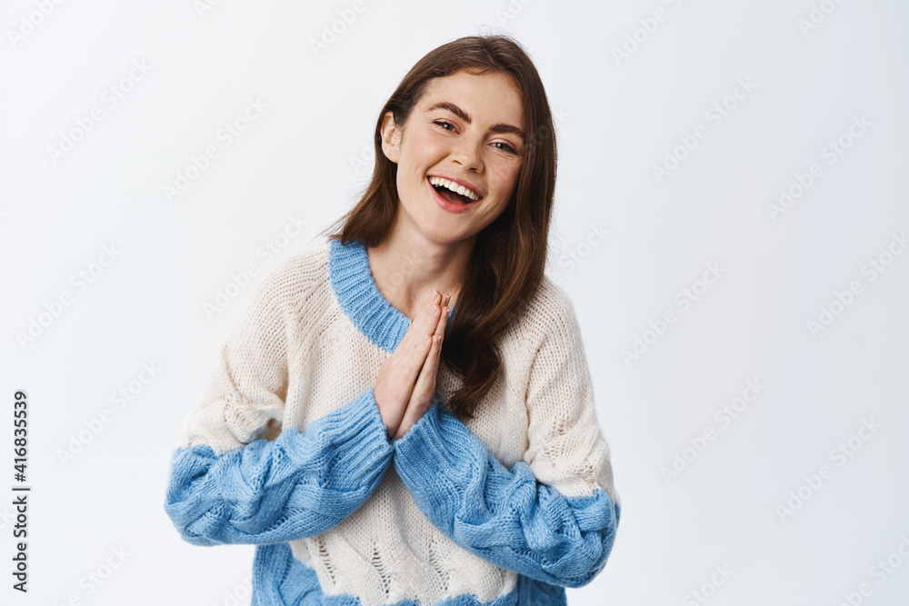 Cheerful cute woman say thank you, holding hands pressed together in pray and smiling grateful, wearing sweater, express appreciation and gratitude, white background Cheerful cute woman say thank you, holding hands pressed together in pray and smiling grateful, wearing sweater, express appreciation and gratitude, white background