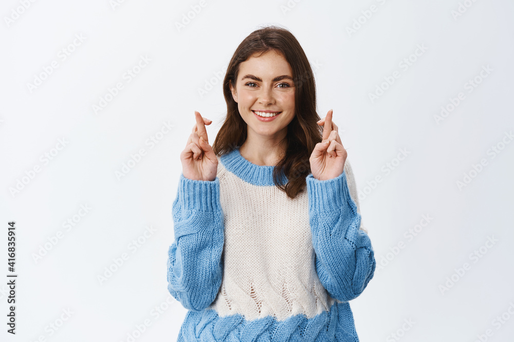 Girl with high hopes making wish, cross fingers good luck and smiling, praying or hoping for positive result, standing against white background Girl with high hopes making wish, cross fingers good luck and smiling, praying or hoping for positive result, standing against white background