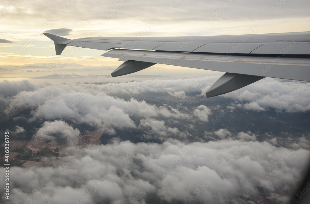 Plane wing in a flight and dramatic cloudscape white clouds over europe