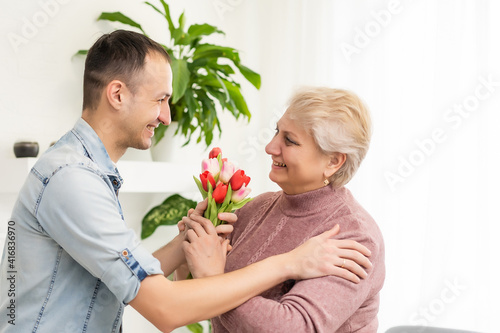 Young man come home to surprise his mother with bouquet of flowers