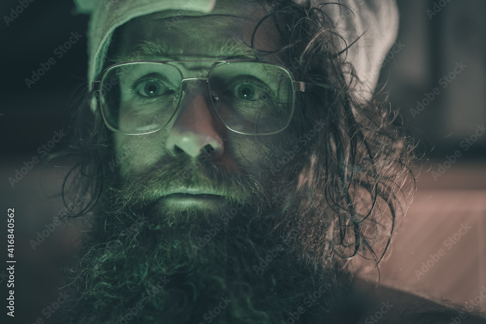 Strange man with long hair and beard drying his had with a towel wrapped around his head. Weird drying procedure of hair for a man lit by strange green dramatic lighting. Strange man with long hair and beard drying his had with a towel wrapped around his head. Weird drying procedure of hair for a man lit by strange green dramatic lighting.