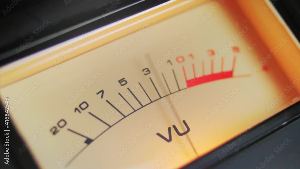 Close up full frame a highlighted analog VU meter with moving needle. A classic symbol of audio recording and music Close up full frame a highlighted analog VU meter with moving needle. A classic symbol of audio recording and music