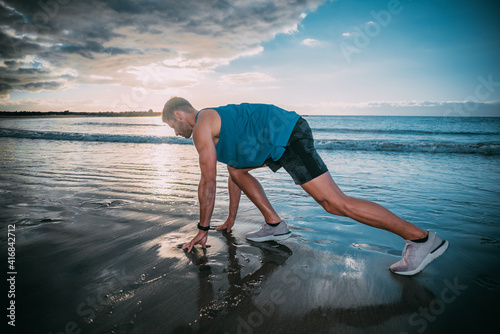 a young man exercises on the beach at sunset on a beach