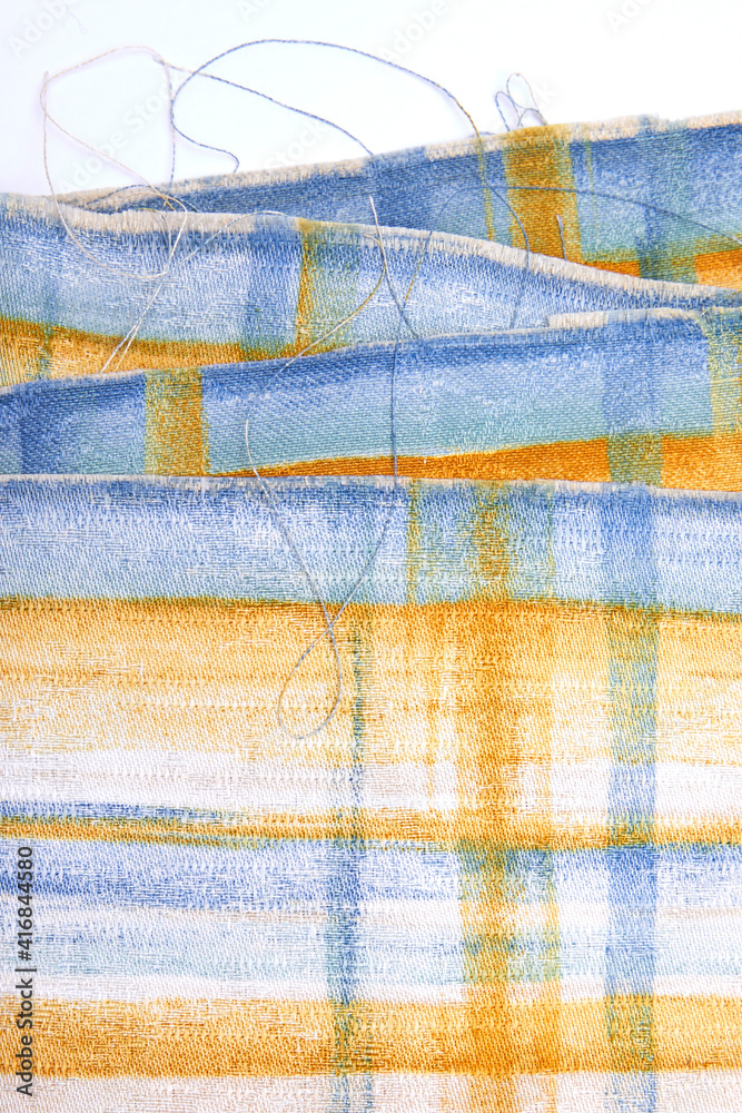 Piece of colourful tattered fabric with horizontal and vertical lines pattern on white background Piece of colourful tattered fabric with horizontal and vertical lines pattern on white background