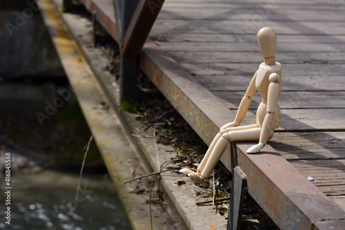 Maniquí de madera sentado en el puente de un río
