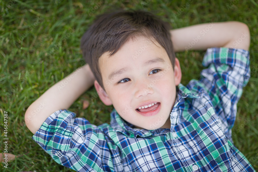 Thoughtful Mixed Race Chinese and Caucasian Young Boy Relaxing On His Back Outside On The Grass Thoughtful Mixed Race Chinese and Caucasian Young Boy Relaxing On His Back Outside On The Grass