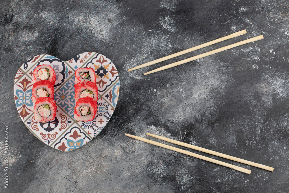 Tasty sushi rolls with red caviar on heart-shaped plate Tasty sushi rolls with red caviar on heart-shaped plate