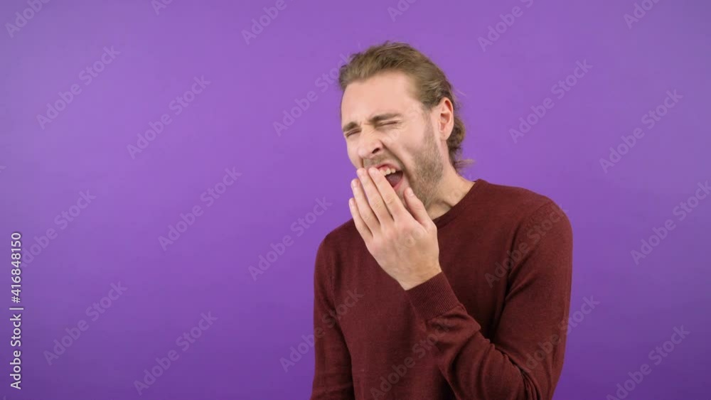 tired sleepy man yawns over isolated purple background. 4K tired sleepy man yawns over isolated purple background. 4K