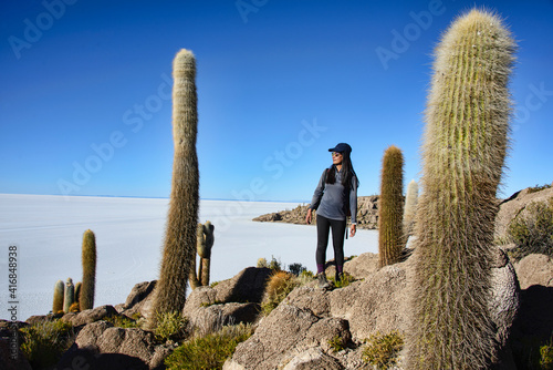Tourist posing next to a Giant cardon cacti (Echinopsis atacamensis) on Isla Incahuasi, Salar de Uyuni, Bolivia photo