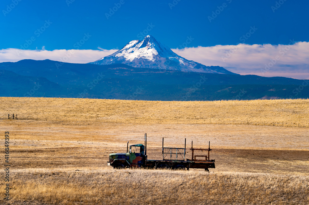 Naklejka premium A farm truch in a dry pasture on a farm near Dufur Oregon, with Mt Hood in the background.