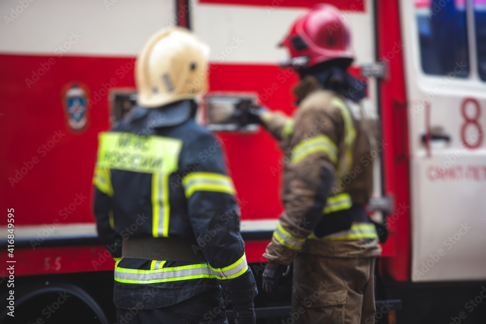 Group of fire men in uniform during fire fighting operation in the city streets, firefighters with the fire engine truck fighting vehicle in the background, emergency and rescue Group of fire men in uniform during fire fighting operation in the city streets, firefighters with the fire engine truck fighting vehicle in the background, emergency and rescue