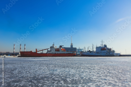Massive different ship vessels trapped in ice tries to break and leave the bay between the glaciers, icebreaker and carrier vessel, winter blue sky view