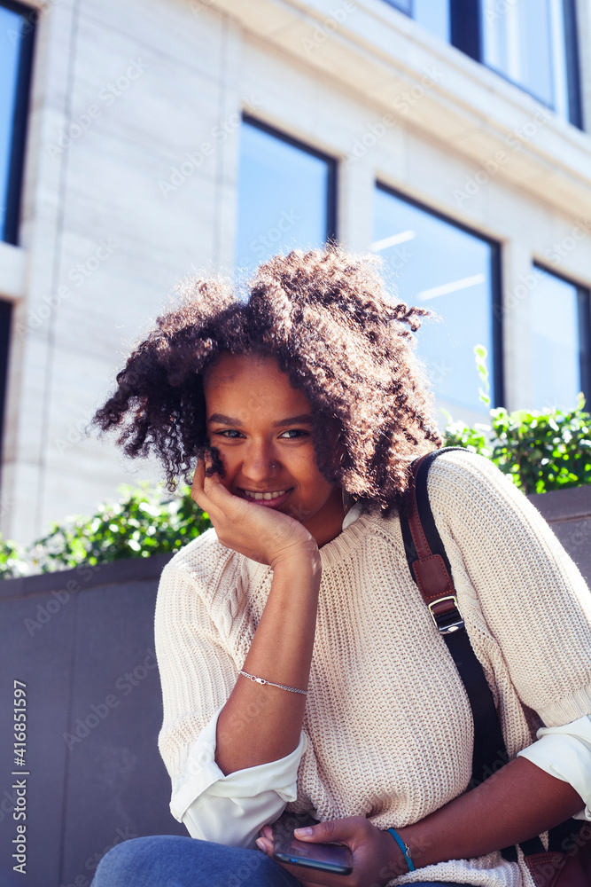 Fototapeta premium young pretty african girl posing cheerful on city background, lifestyle outdoor people concept