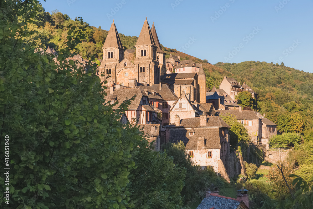 The quaint and charming medieval French village of Conques, Aveyron, and Abbey Church of Sainte-Foy, a popular summer tourist destination in the Occitanie region of France.