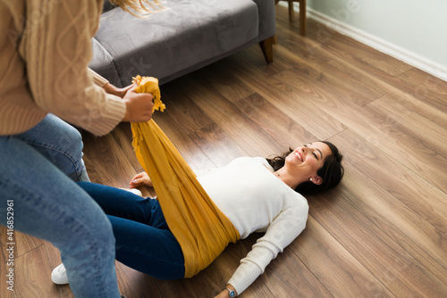 Woman feeling happy while a doula wraps a rebozo around her belly photo