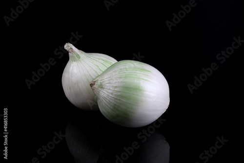 Pair of unsliced onions, black background reflection