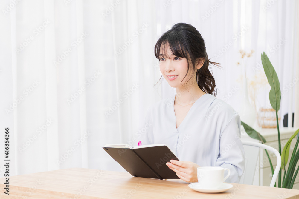 部屋でノートにメモを書く若い女性