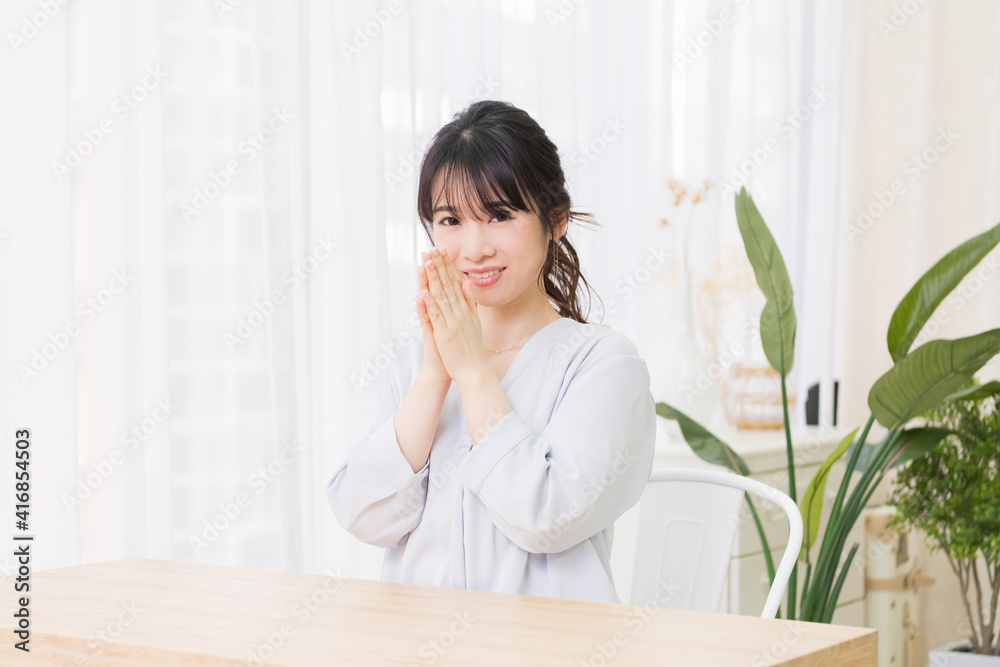 部屋でお願いのジェスチャーをする若い女性