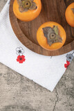 Delicious ripe persimmon fruits placed on wooden plate