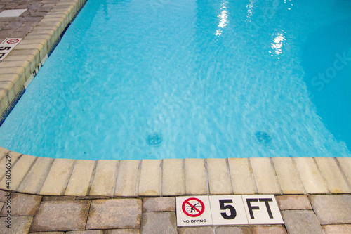 Warning sign of no diving into the shallow end of a swimming pool.