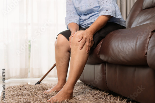 senior woman suffering from knee pain at home, health problem concept