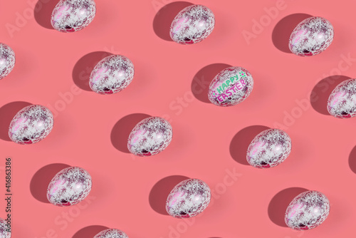 A pattern of shiny fashionable eggs on a pink background. Concept of Easter