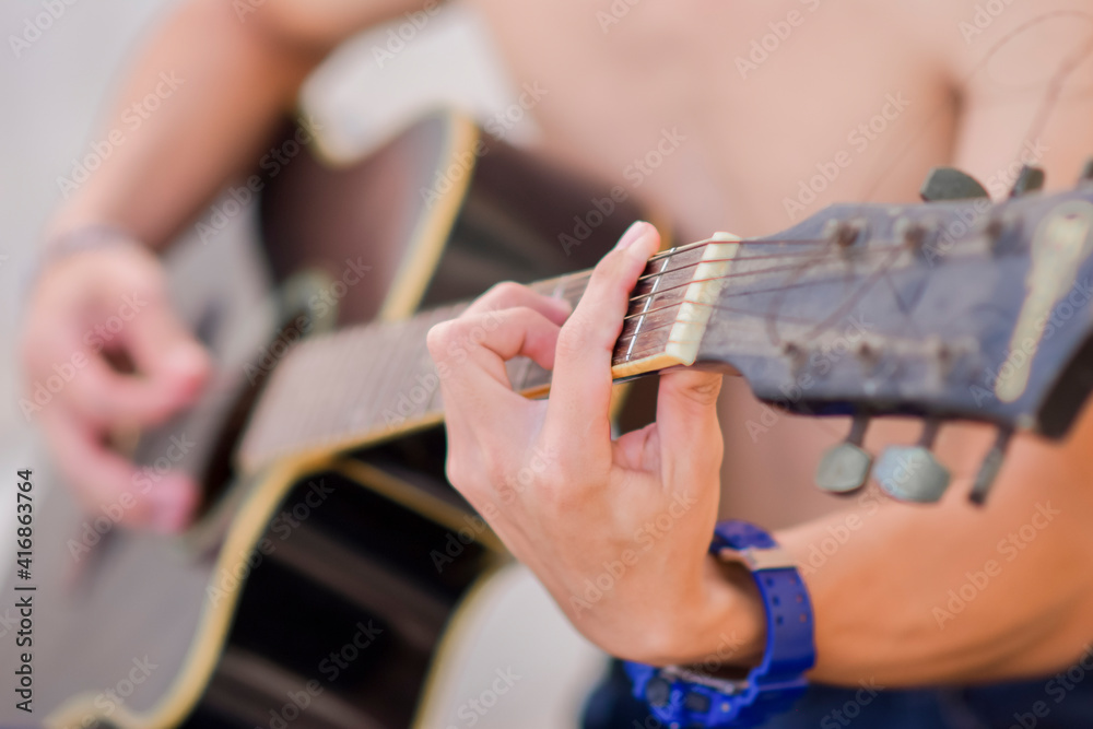 A male hand close up playing the guitar