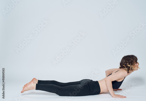 A woman is doing exercises for an even posture on a light background in full growth