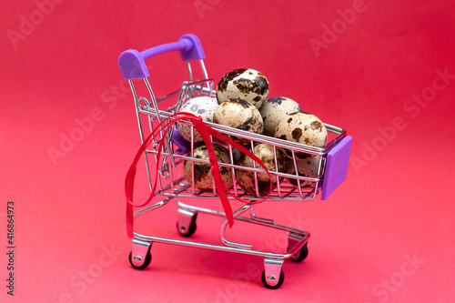 Supermarket trolley with eggs on a red background. Preparing for the Easter holidays. The photo photo