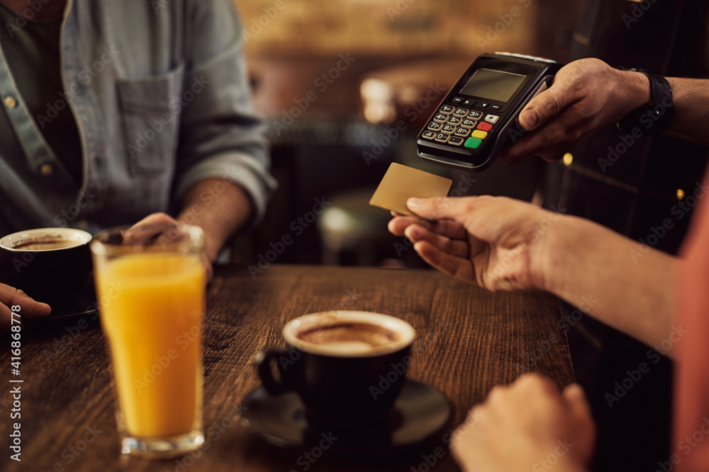 Close-up of woman paying with credit card in a cafe. Close-up of woman paying with credit card in a cafe.